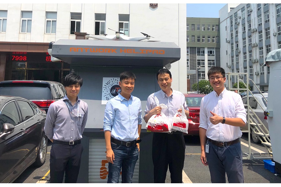 2019年、中国アントワーク社のドローンにより配達されたKFCチキンを手に持つ、産業用ドローン事業のテラドローン（東京）代表とアントワーク社社員（画像：テラドローン）