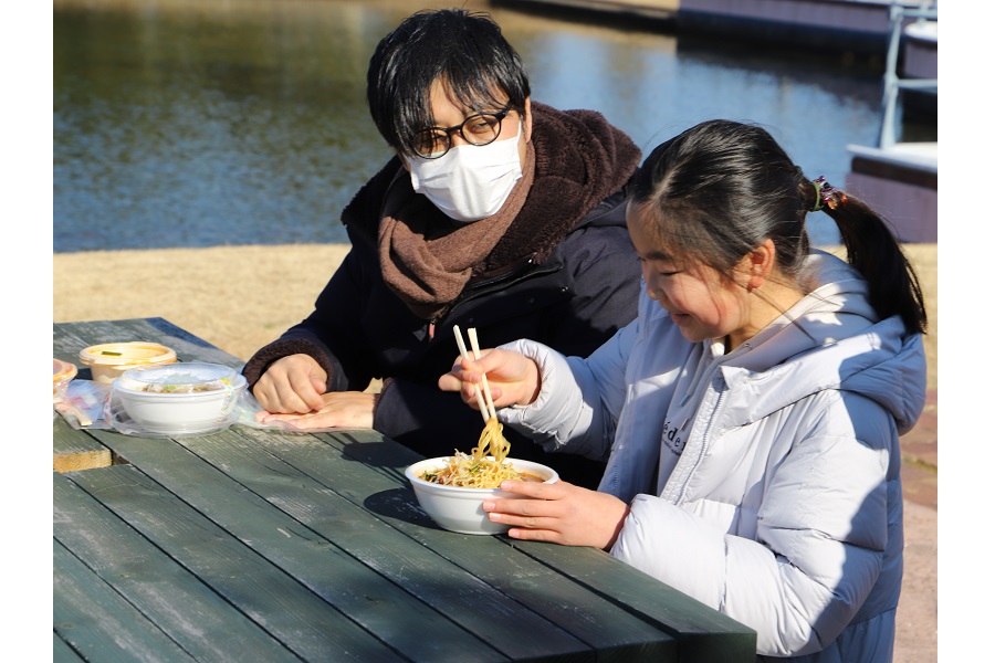 2022年2月、千葉県で行われた実証実験。ドローン配送された熱々の勝浦タンタンメンを食べる参加者（画像：NEXT DELIVERY）