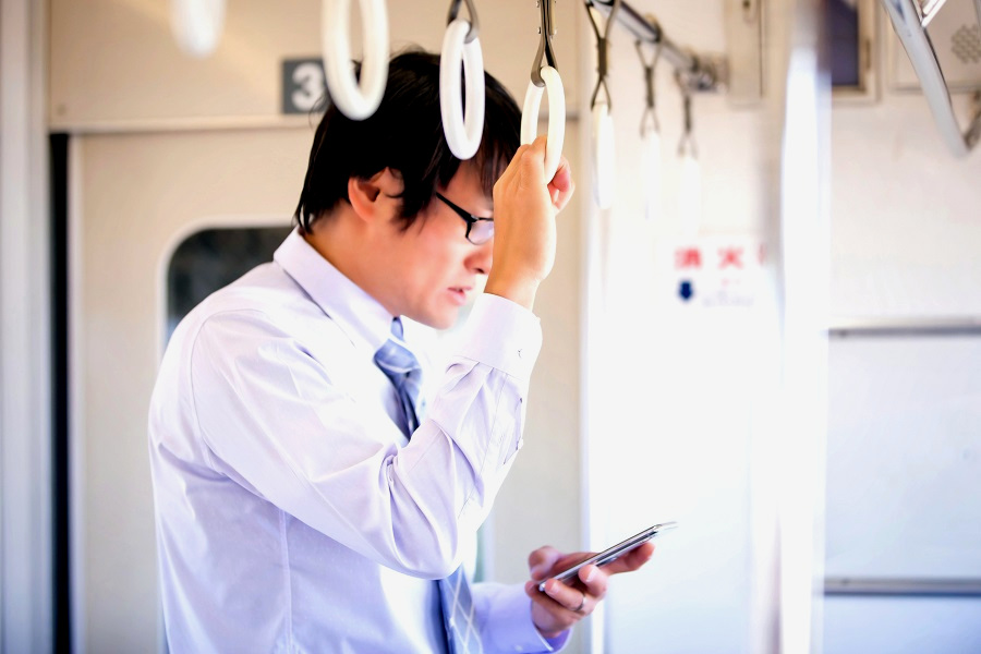 電車の中でスマートフォンを操作する人のイメージ（画像：写真AC）