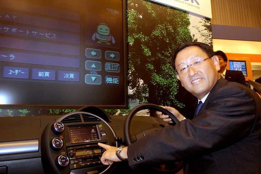 2002年8月撮影。トヨタ自動車が発表した新しい車載情報ネットワークサービス「G-BOOK」のコントロールパネルに手をやる豊田章男常務取締役（当時）。カーナビと連動した車載端末を通じて交通、レジャー関連などの多様な情報提供を行うサービス。港区の明治記念館にて（画像：時事）