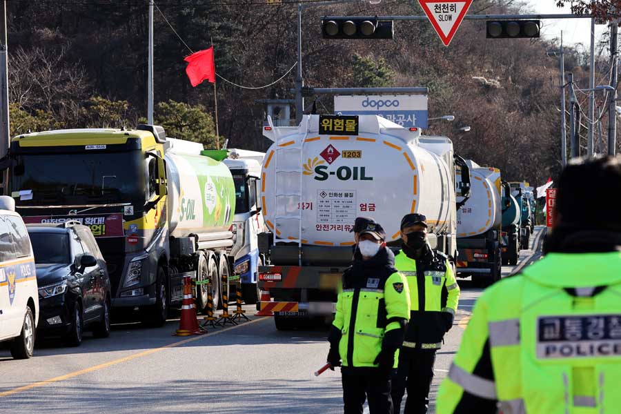 韓国・ソウルの大韓石油パイプライン社支店前で、ストライキ中の運転手の横を、非組合員の運転するタンカー（右）が警察の保護下で通過する。2022年12月2日撮影（画像：EPA＝時事）