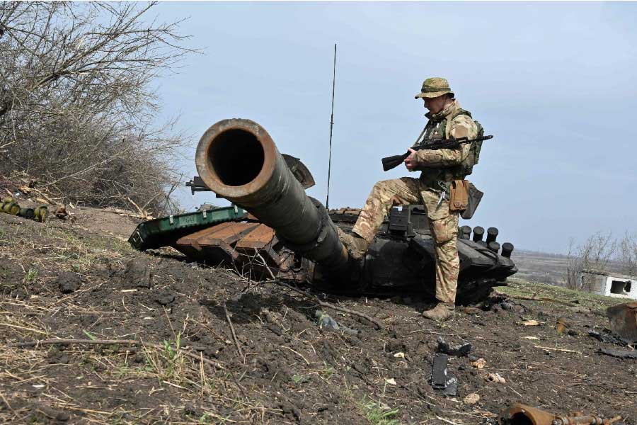 ロシアの戦車の残骸を確かめるウクライナ兵。2022年4月1日撮影（画像：AFP＝時事）