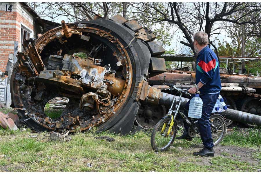 破壊されたロシア軍の戦車を見るウクライナ住民。2022年5月15日撮影（画像：AFP＝時事）