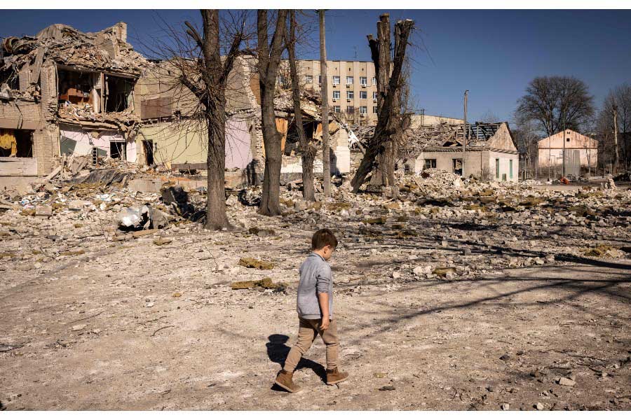 ロシア軍に破壊された学校の前を歩くウクライナの子ども。2022年3月23日撮影（画像：AFP＝時事）