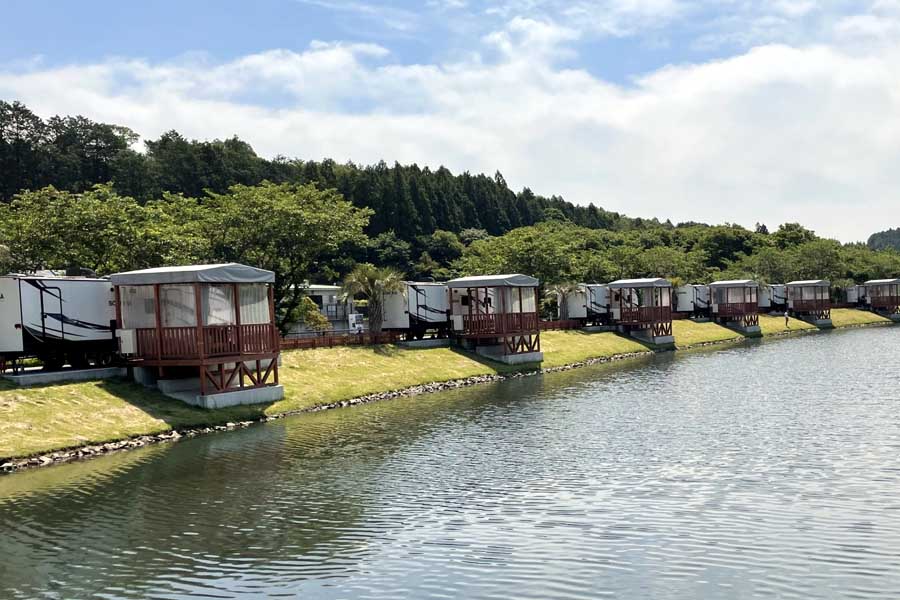 池のそばに立ち並ぶ複数の「トレーラーハウス」（画像：写真AC）