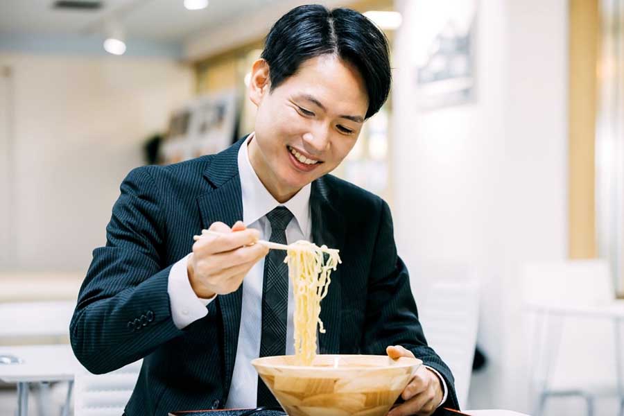 距離運転中のビジネスマンの食事の様子(画像:写真AC)