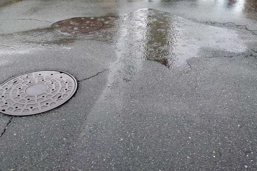 雨にぬれたマンホールと水たまり（画像：写真AC）
