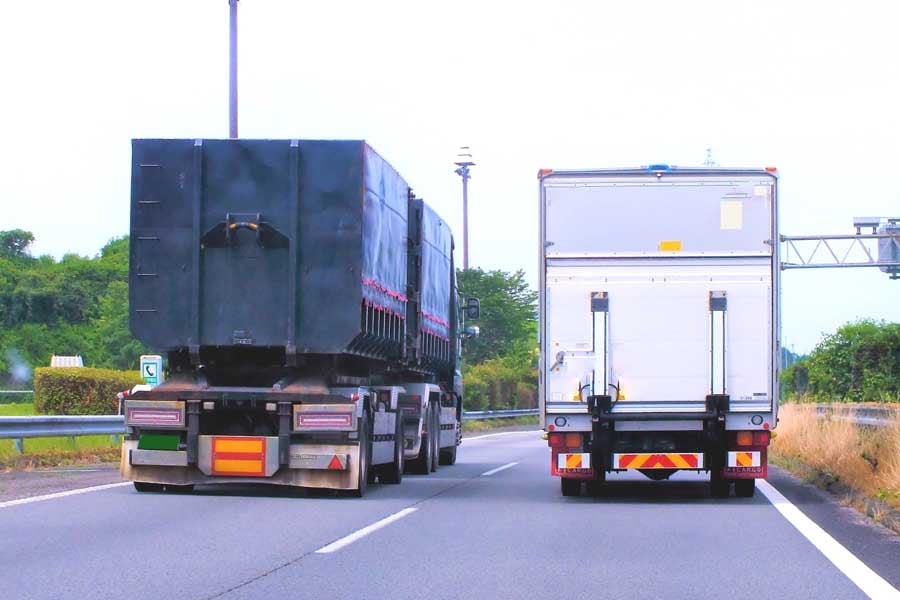 道路を走るトレーラーとトラック(画像:写真AC)