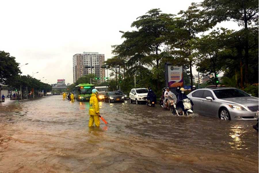 ハノイ市日系スーパーイオンモールロンビエン前の通りで水位の低い方へ誘導する職員（画像：Trang Thu Do Hanoi）