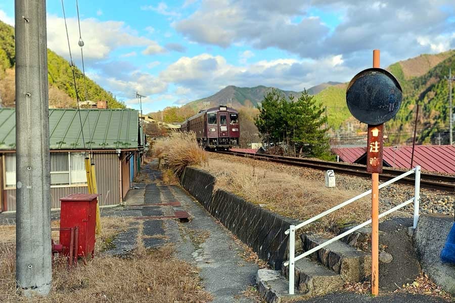 「中才鉱山住宅」のそばを通るわたらせ渓谷鉄道線の列車（画像：大塚良治）