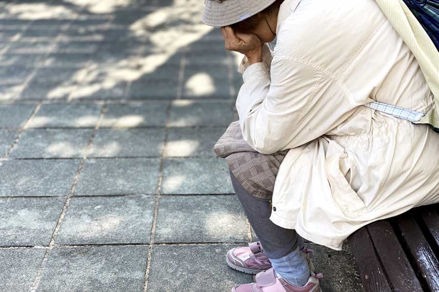 ベンチでうなだれる高齢女性（画像：写真AC）