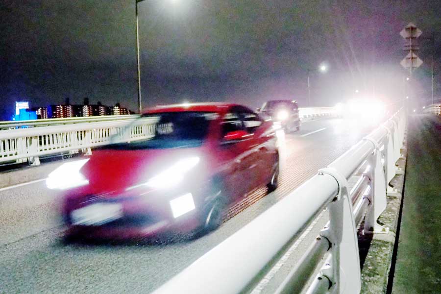 ヘッドライトをつけて走行する自動車（画像：写真AC）