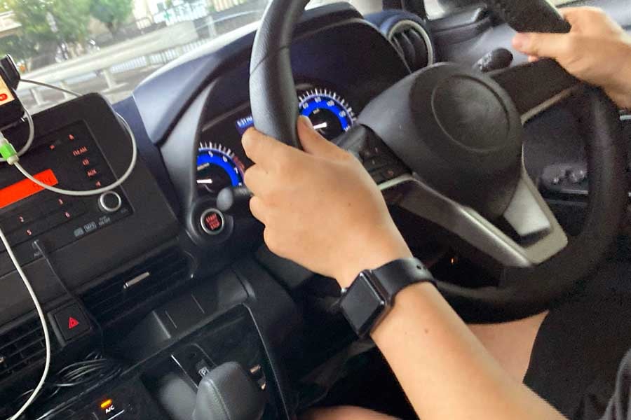 スマートフォンのカーナビを見ながら車の運転をする人（画像：写真AC）