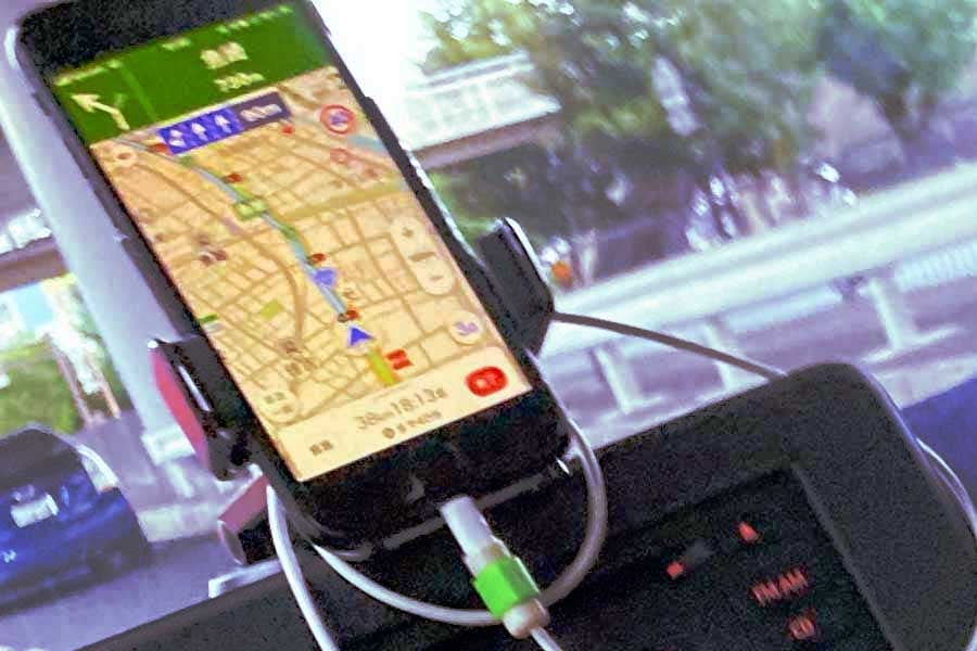 スマートフォンのカーナビを見ながら車の運転をする人(画像:写真AC)