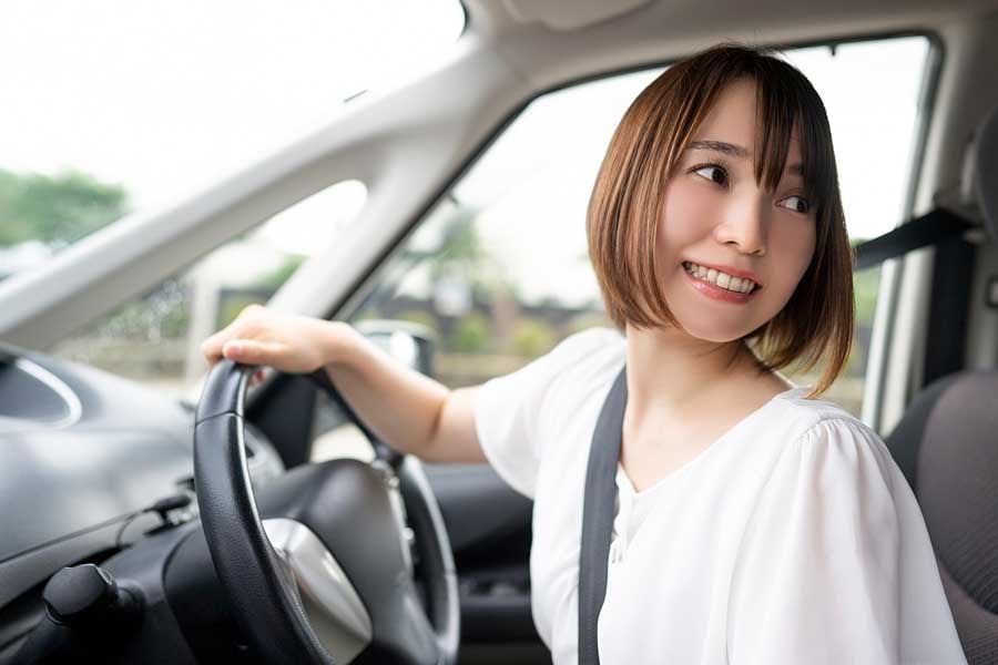 車をバックで駐車する女性（画像：写真AC）