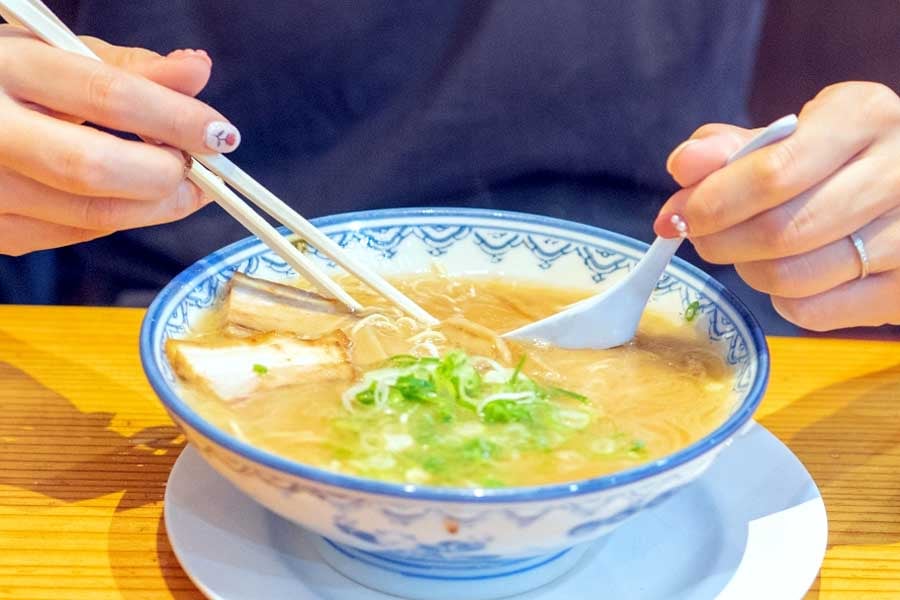 カウンター形式の店舗でラーメンを食べる人(画像:写真AC)