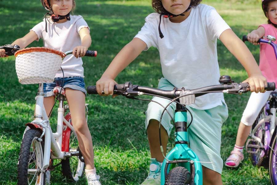 芝生の広場で自転車に乗る子どもたち(画像:写真AC)