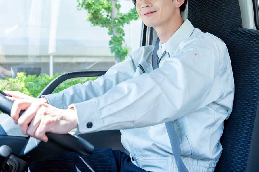 トラックを運転する若い男性(画像:写真AC)