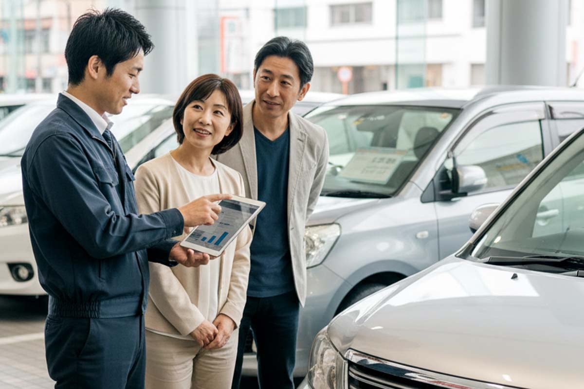 中古車販売店で説明を受ける夫婦のイメージ。生成AIで作成。