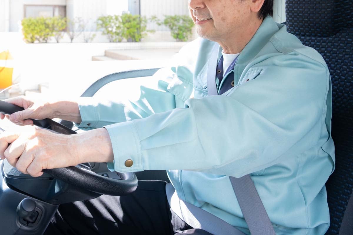 トラックを運転する男性ドライバー（画像：写真AC）