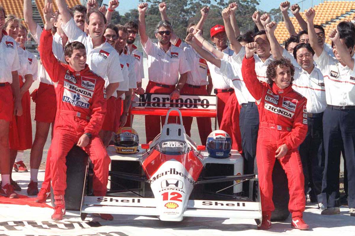 年間チャンピオンに決まり、マクラーレンホンダのスタッフ、チームメイトのプロスト（右）と喜ぶセナ。オーストラリアで。1988年11月12日撮影（画像：AFP＝時事）