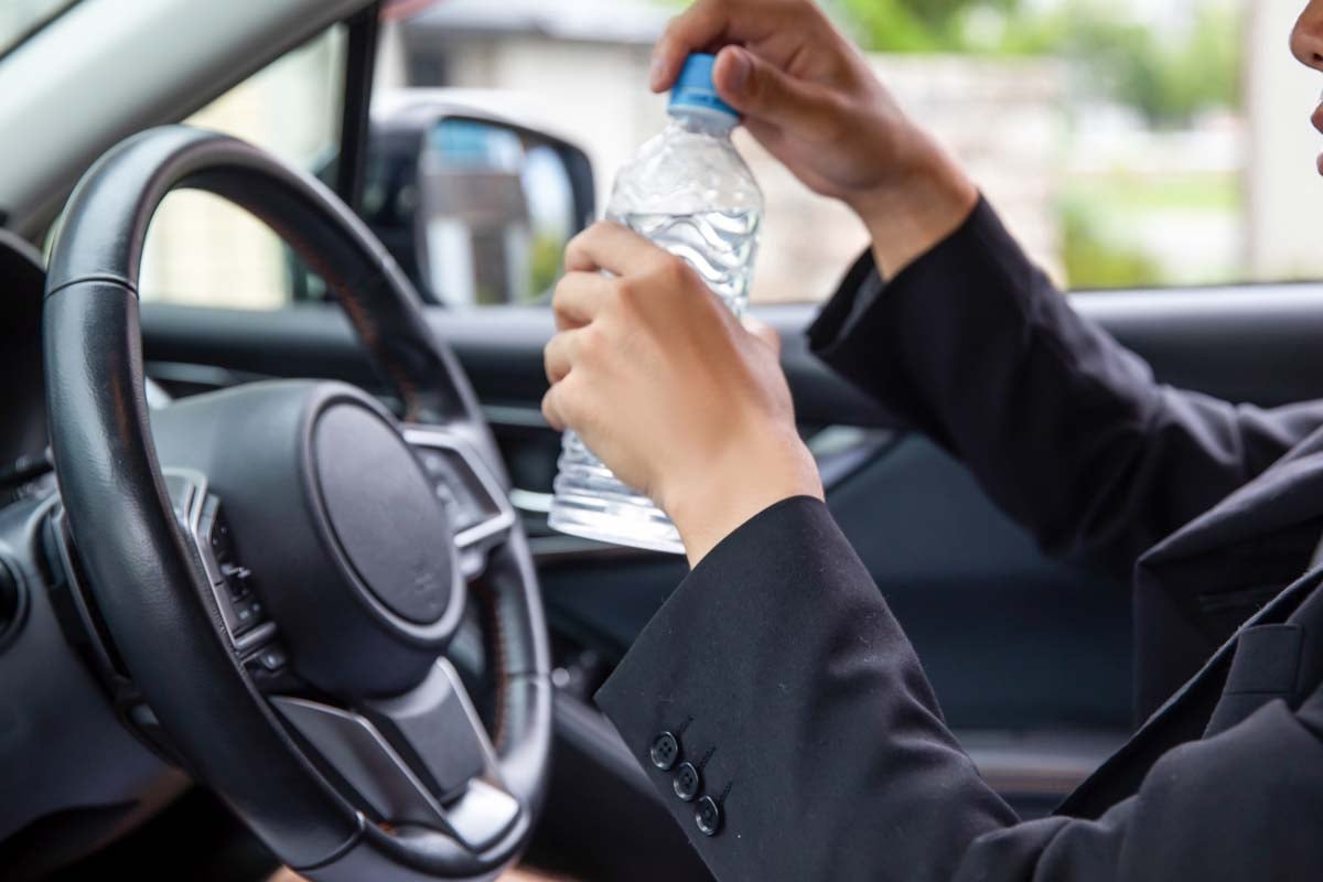 運転席で水を飲む男性（画像：写真AC）