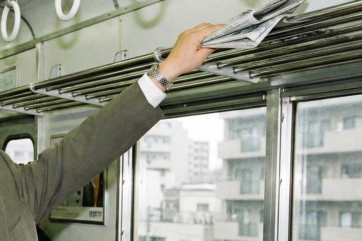 網棚の新聞を取るサラリーマンのイメージ。